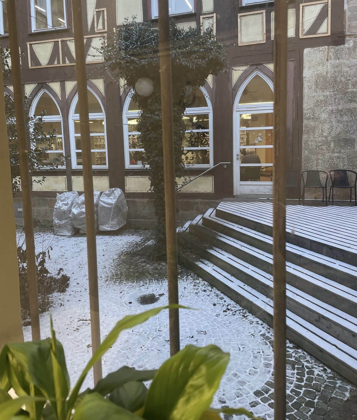 Blick in den verschneiten Innenhof der Esslingen Pfleghof Stadtbücherei mit barrierefreier Rampe und Zugang zur Bibliothek.