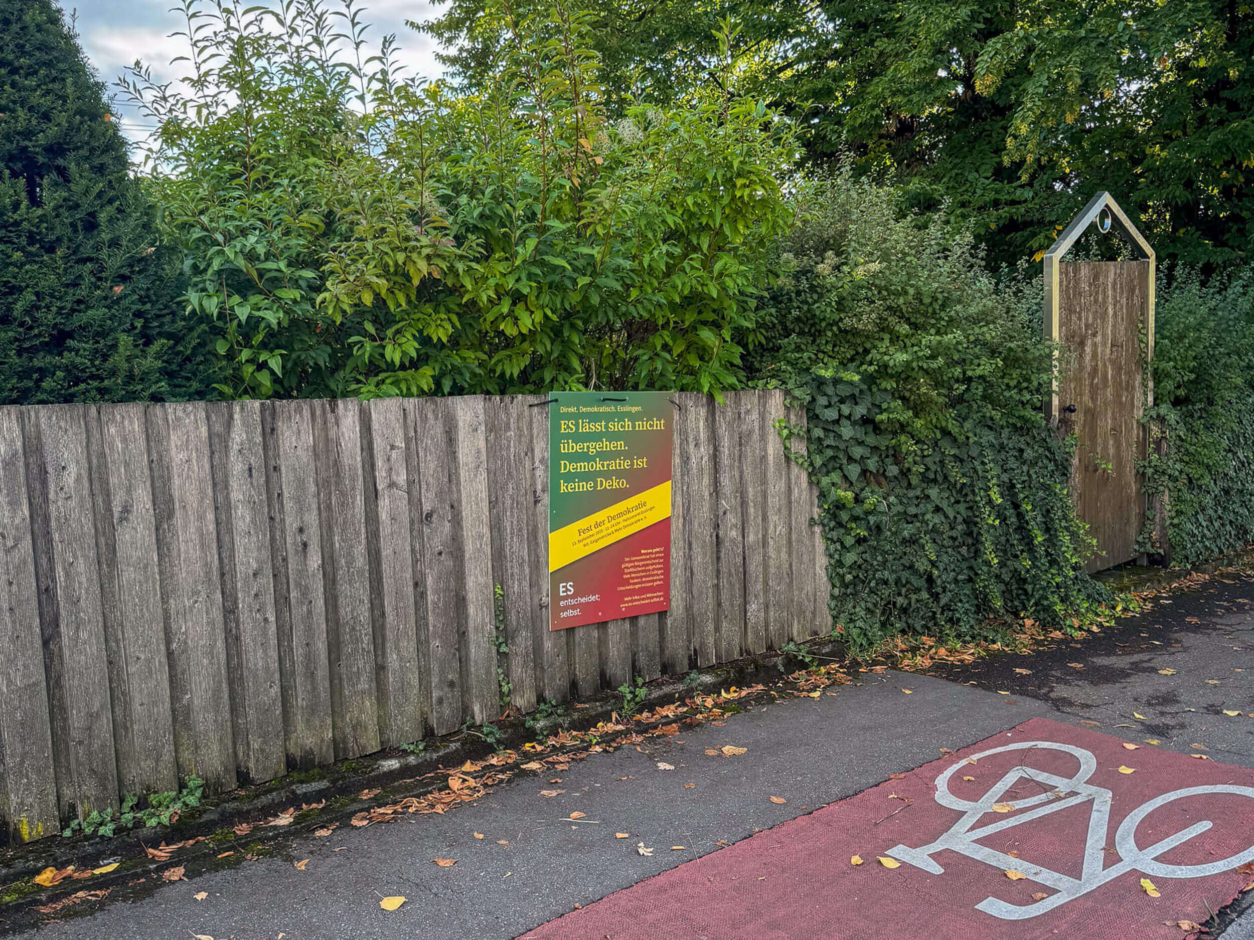 Ein Plakat für das Fest der Demokratie, an einem Gartenzaun befestigt. Das Fest wird von ES entscheidet; selbst. organisiert, um das Thema "Demokratie födern Esslingen" sichtbarer zu machen.